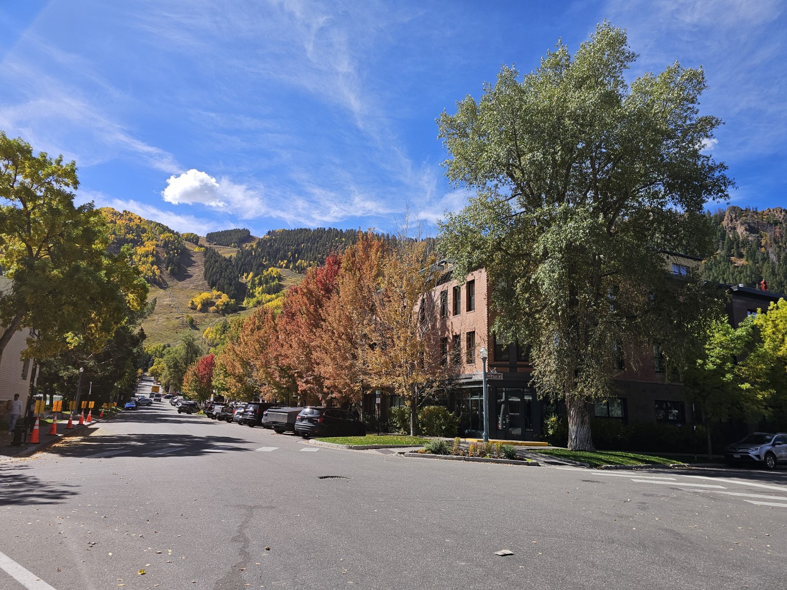 Aspen street lined with fall trees and mountains rising at the end of the road